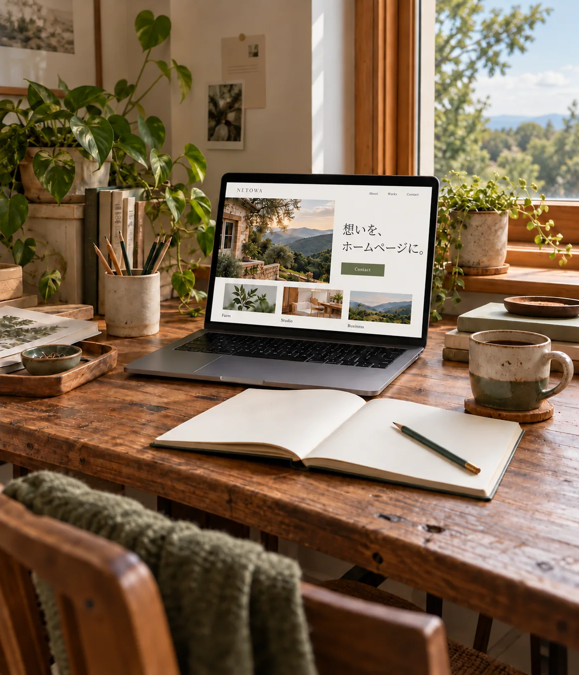 植物と自然光に囲まれた木製デスクとWeb制作のノートPC